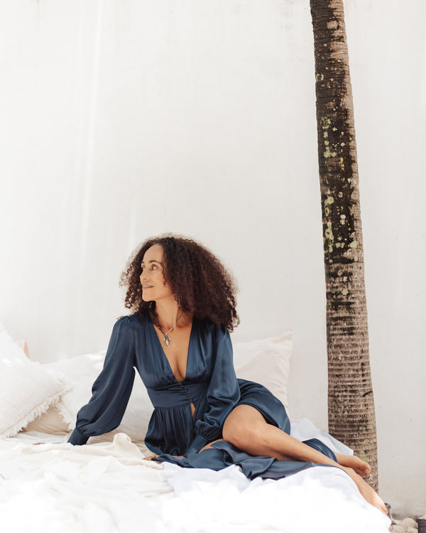 Our English-Jamaican model, Allison, wearing Coco Navy Silk Robe while lounging on a bed - unedited version
